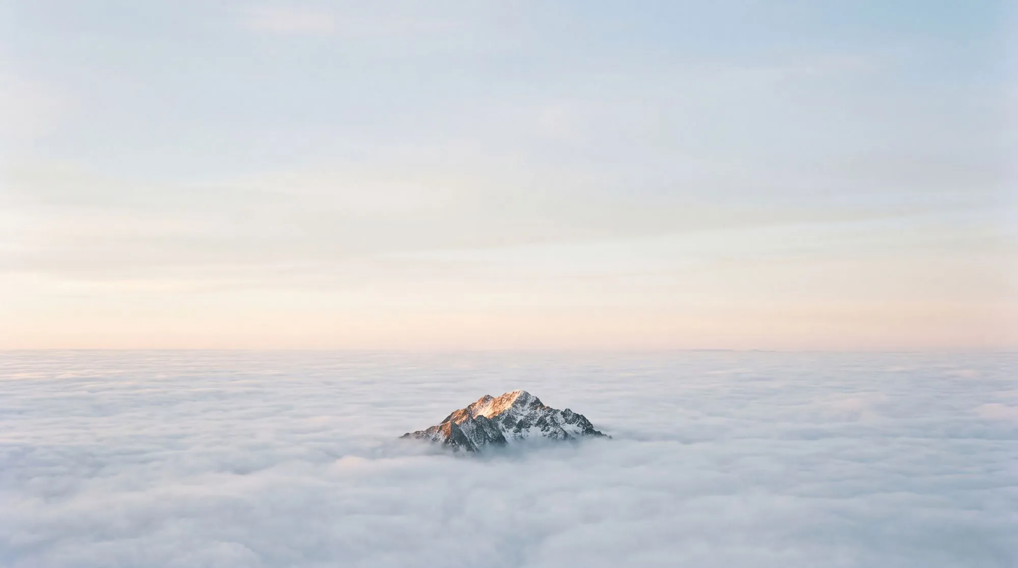 A single mountain peak rising above a sea of clouds